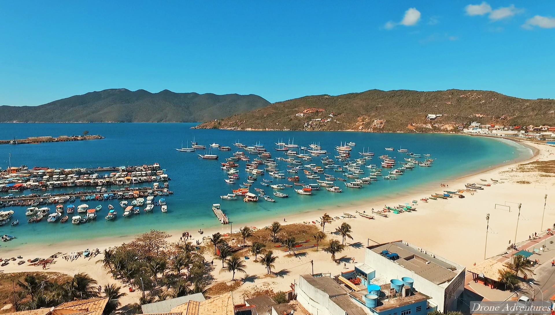 Praia dos Anjos de Arraial do Cabo vista do drone, com o porto de pescadores e a água azul