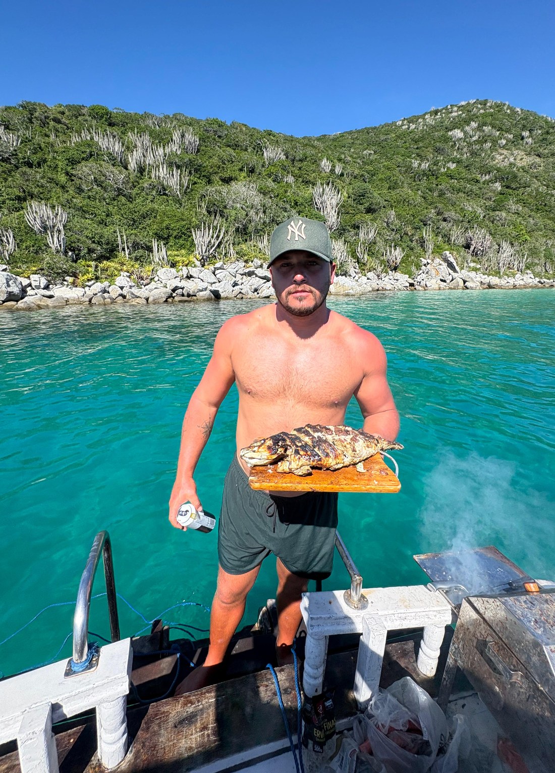 Pescado a la parrilla a bordo del paseo en barco del Massambaba, con el agua turquesa de Arraial do Cabo al fondo