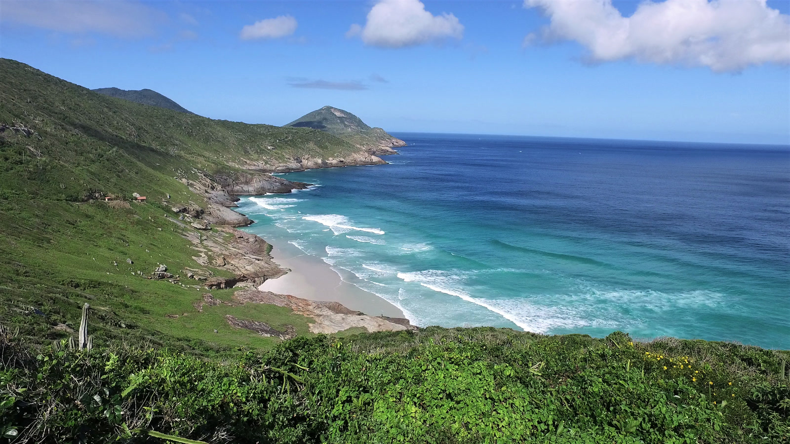 Praia Brava em Arraial do Cabo, praia selvagem de areia branca e mar turquesa cercada por morros verdes, vista da trilha