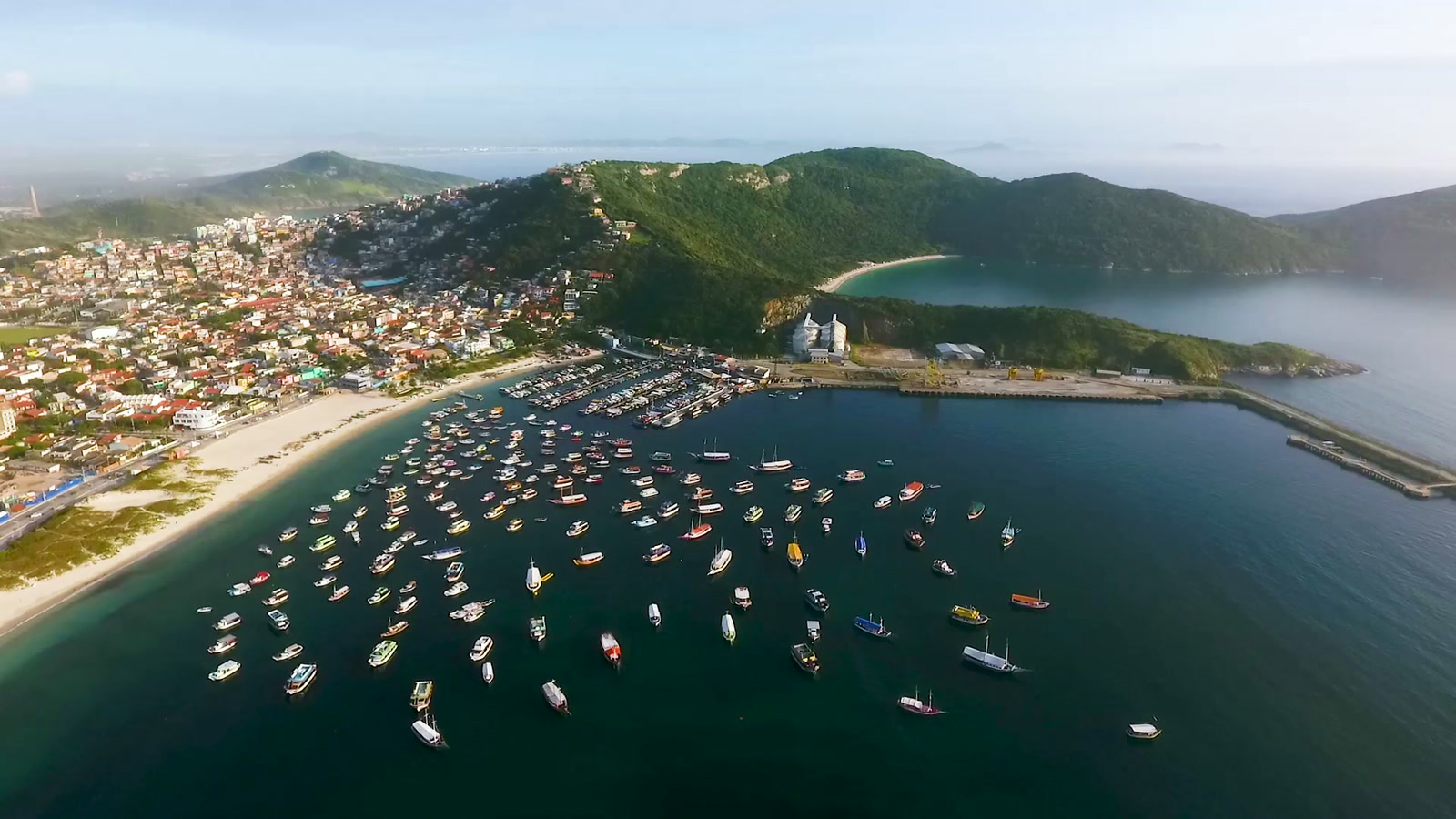 Vista aérea de Praia dos Anjos en Arraial do Cabo, una bahía tranquila con barcos anclados y la ciudad al fondo