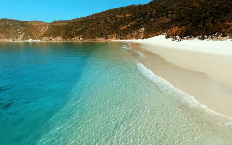 Areia branca e água turquesa rasa nas Prainhas do Pontal do Atalaia